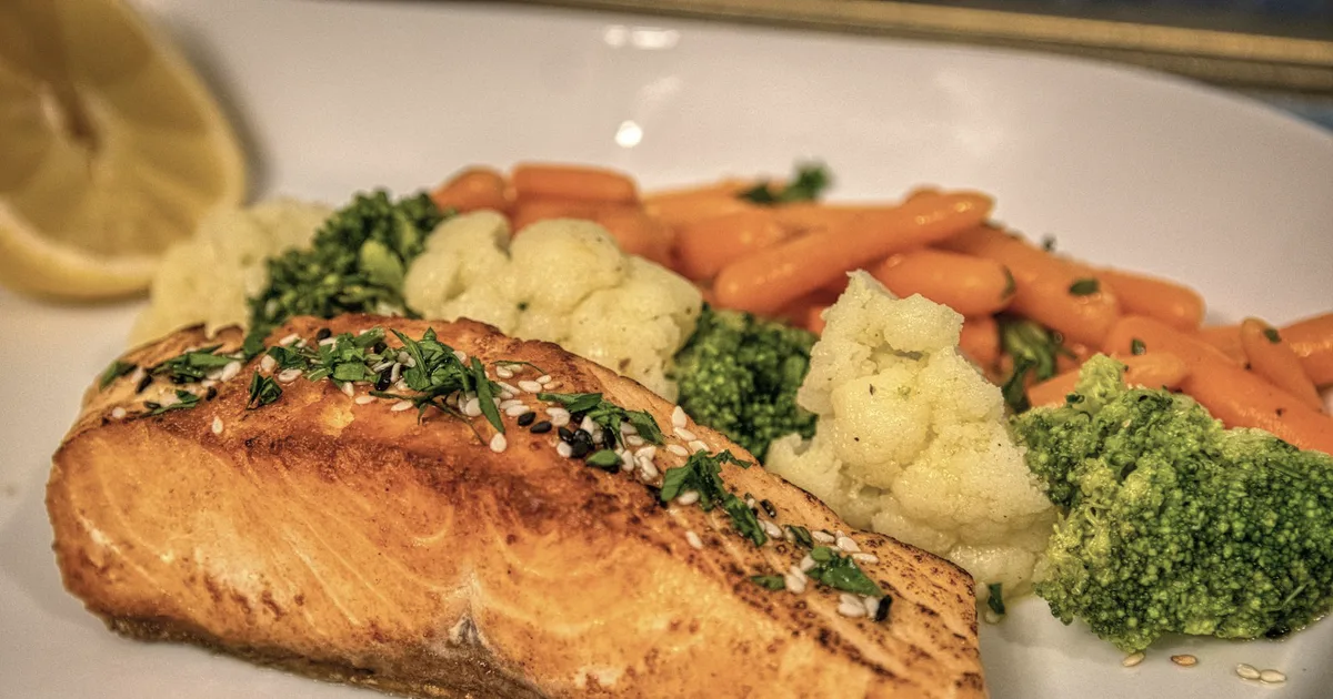 Grilled salmon fillet served with steamed vegetables on a plate