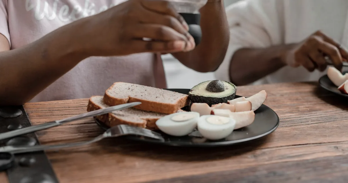 Breakfast with hard-boiled eggs, wholegrain bread and avocado on a wooden table