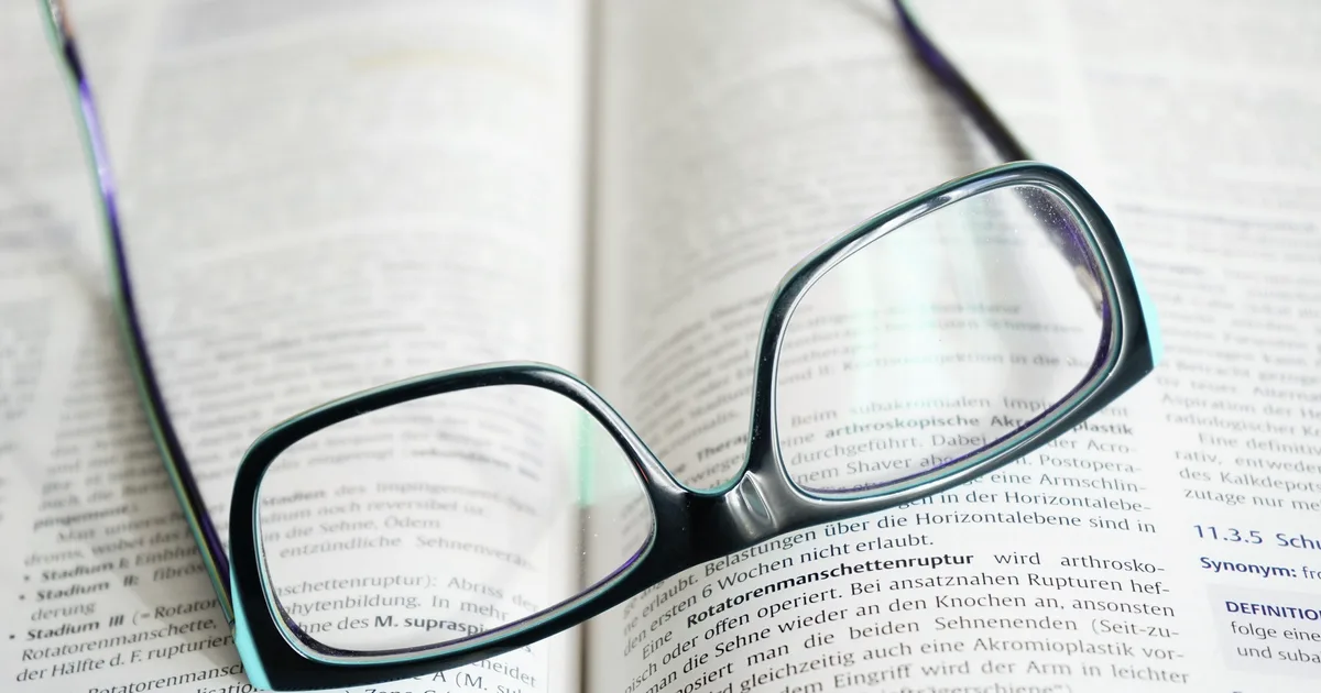 Lunettes de lecture posées sur les pages ouvertes d'un livre, métaphore filée par Annick Vincent dans son livre sur le TDAH