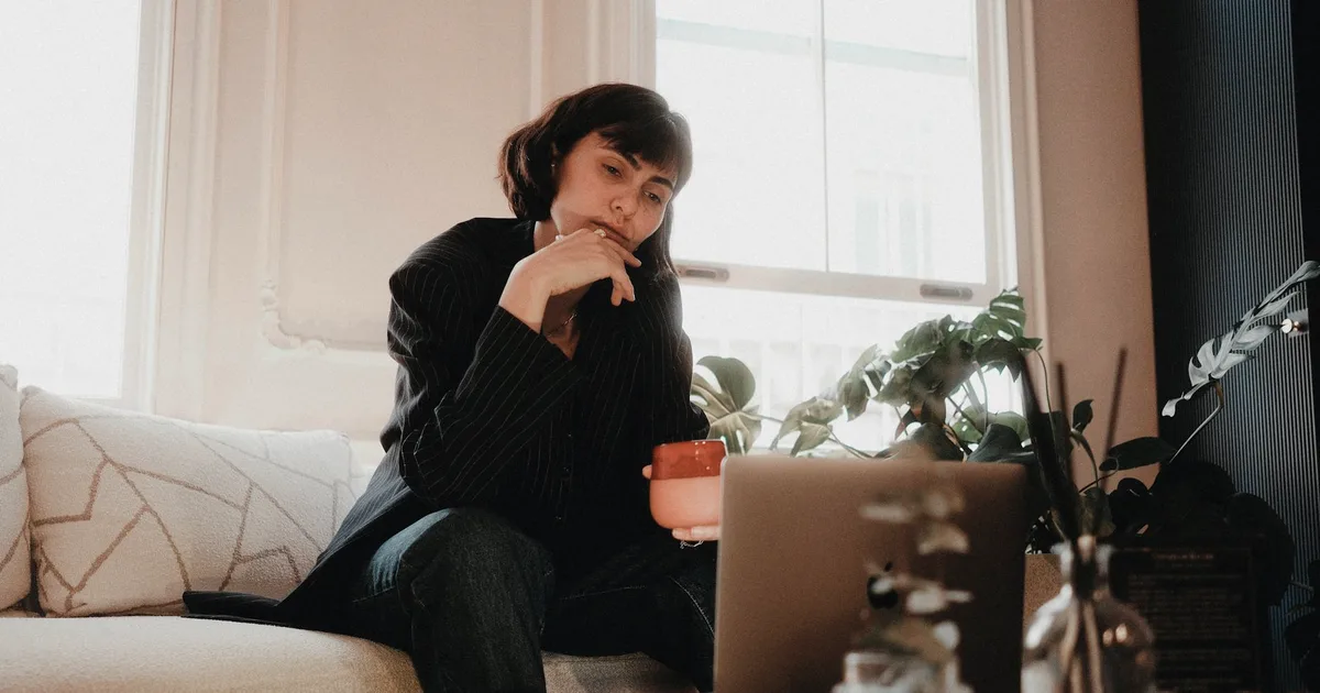 Thoughtful woman at home with a laptop, looking into an ADHD diagnosis