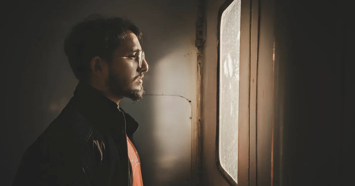Pensive man in profile looking out a window in warm light