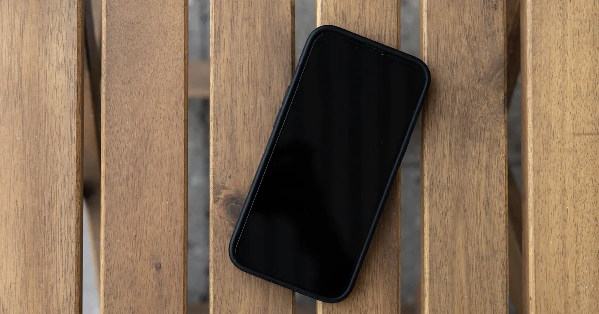 Smartphone with a dark screen lying on a wooden table