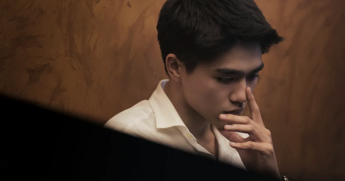 Pensive young man with his hand to his face in warm, low light