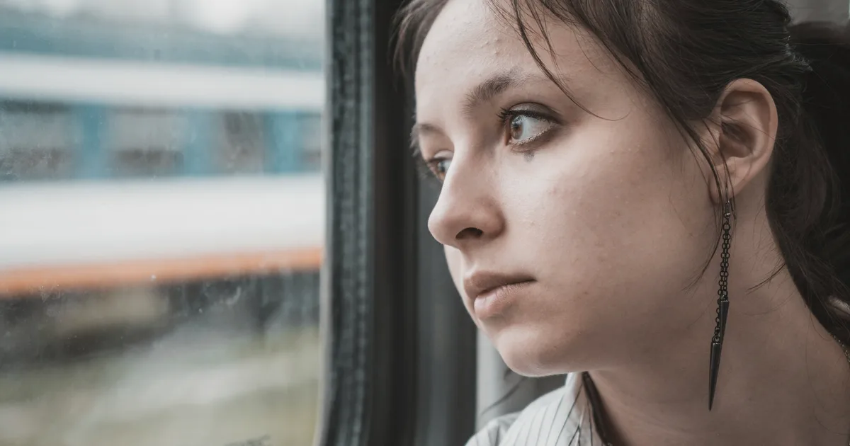 Femme pensive regardant par la fenêtre d'un train
