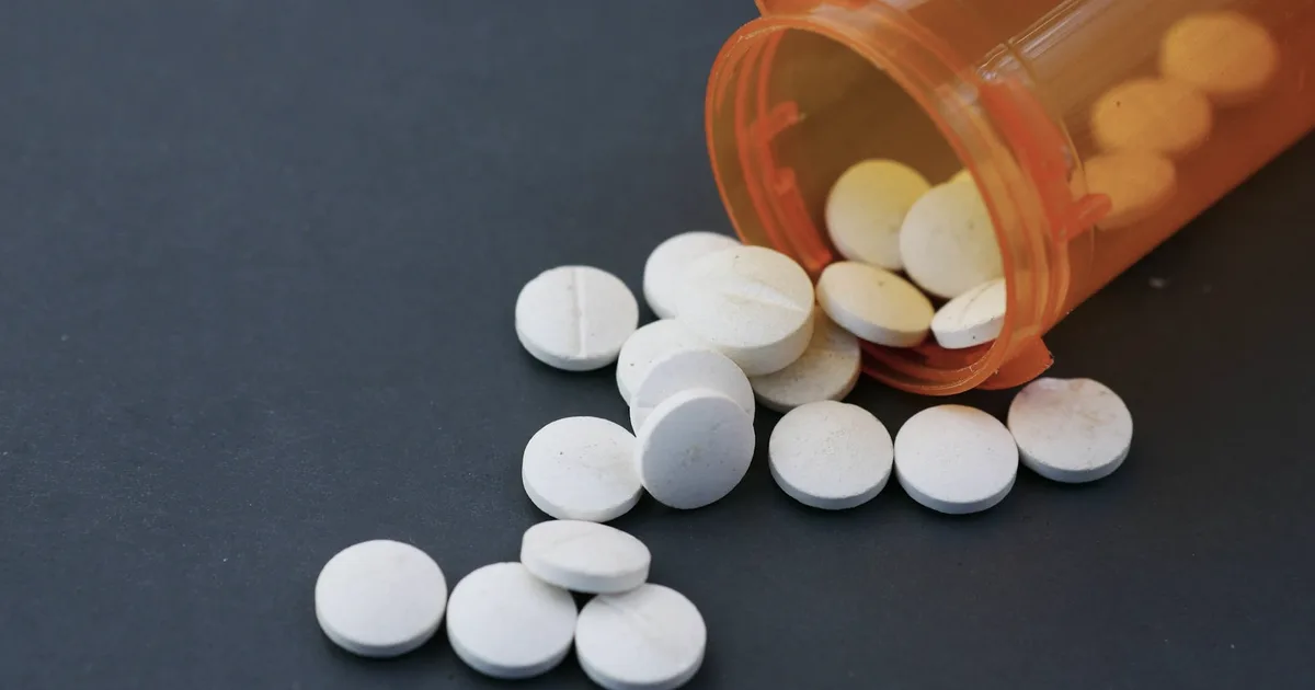 White pills spilling from an orange prescription bottle