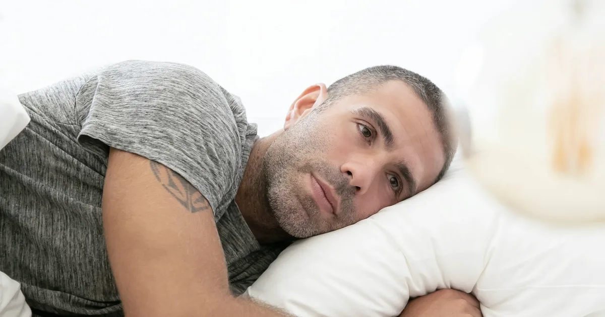 Man lying on a pillow, eyes open, in the morning