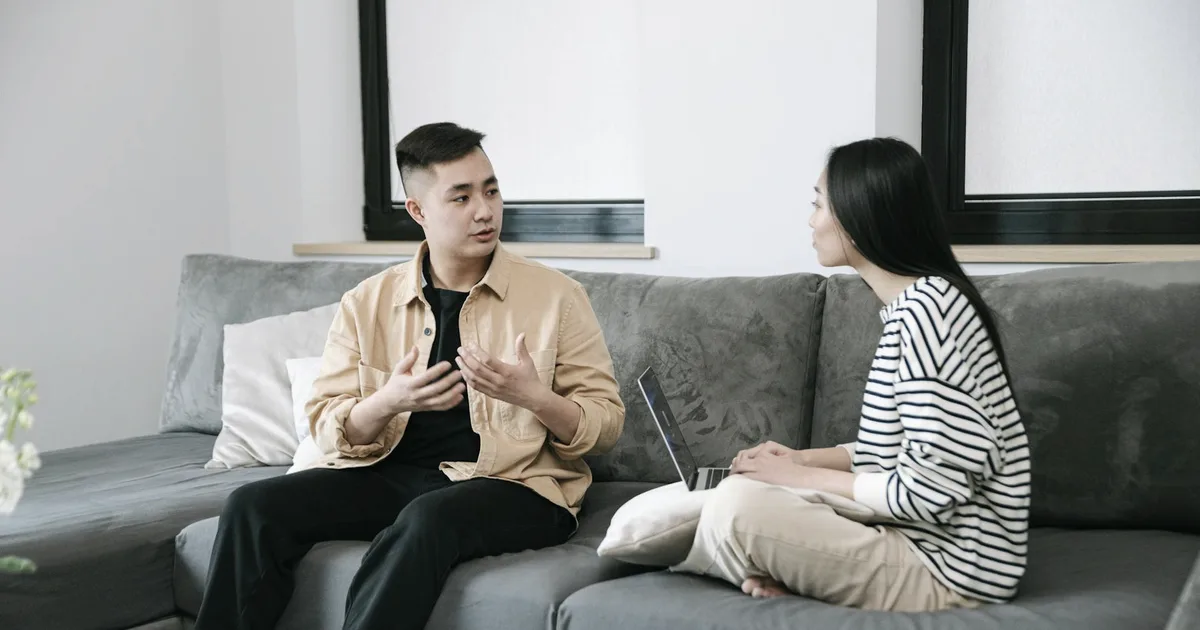 Two people sitting on a sofa, talking calmly