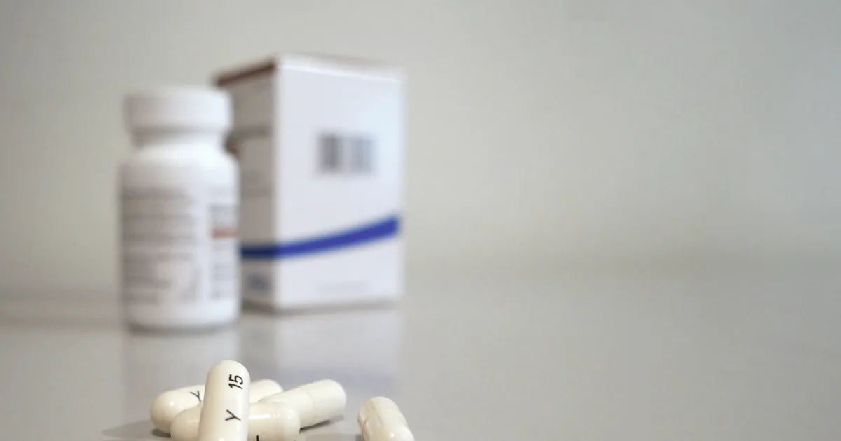 Gélules blanches d'un traitement non stimulant du TDAH posées près d'un flacon de médicament