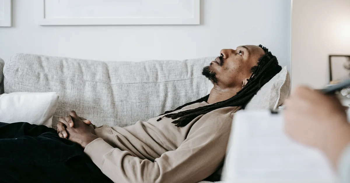 A person lying on a couch, staring blankly ahead