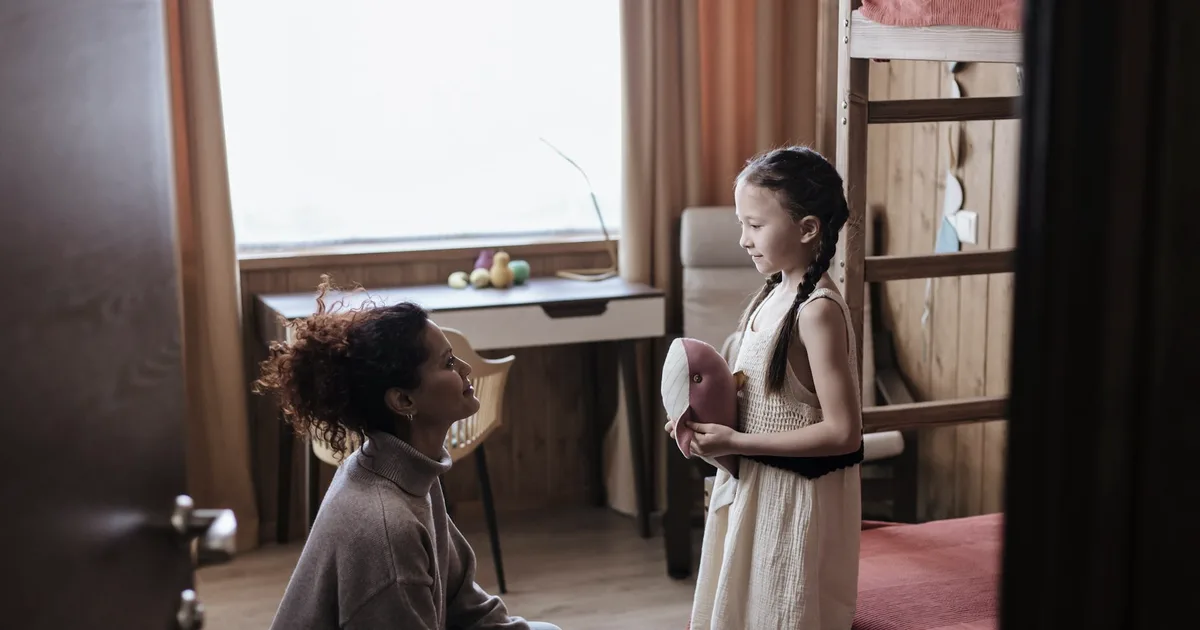 A parent kneeling to their child's level for a calm conversation at home