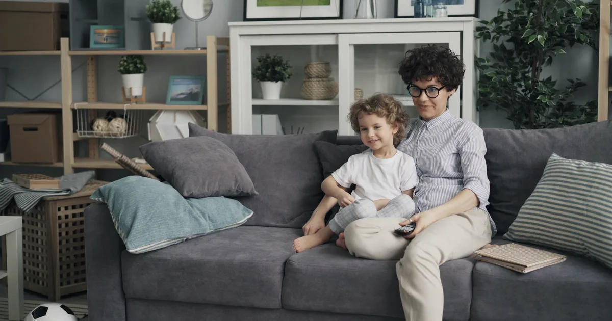 A parent and a young child sitting quietly together on a couch