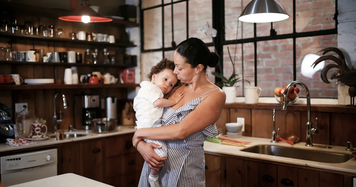 Mother holding her young child in a kitchen, an everyday scene