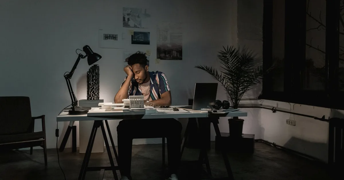 Exhausted person at a desk in the evening, the cost of ADHD masking and compensation
