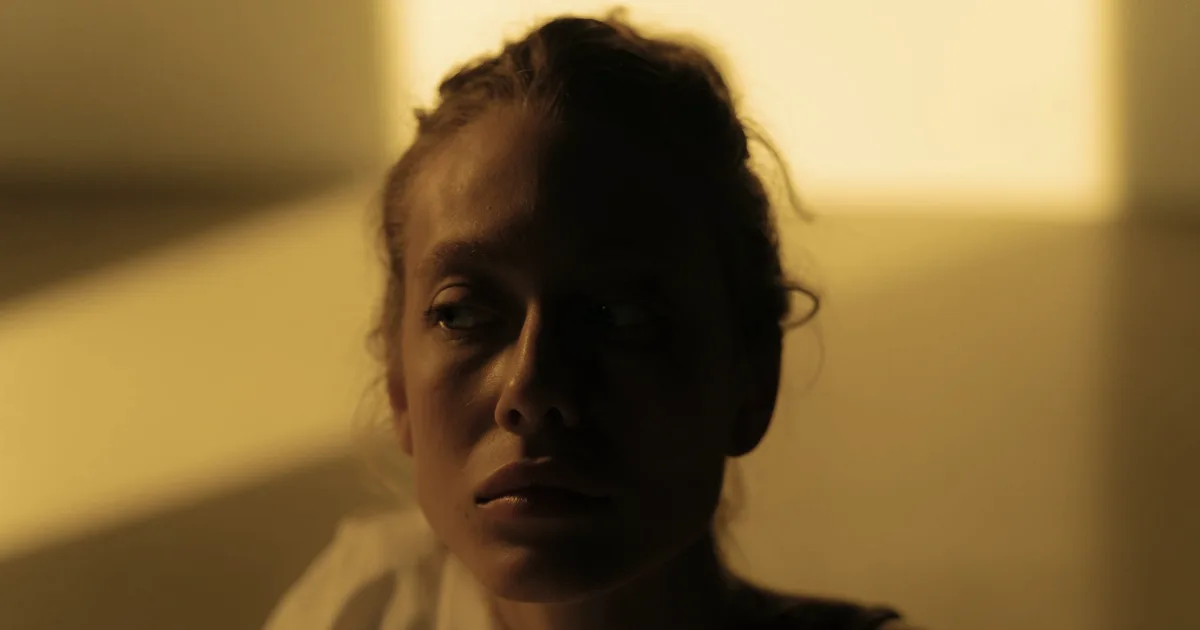 Femme adulte pensive dans une lumière chaude, les symptômes du TDAH chez la femme passent souvent inaperçus