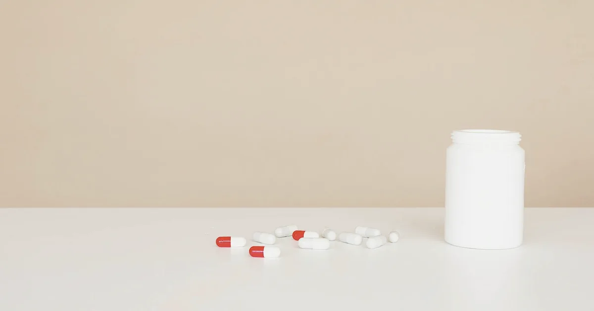 White pill bottle and bupropion capsules on a light beige surface